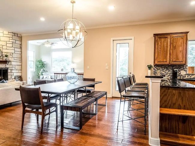 Dining room featuring dark wood-type flooring, a fireplace, ceiling fan with notable chandelier, and ornamental molding | Image 16