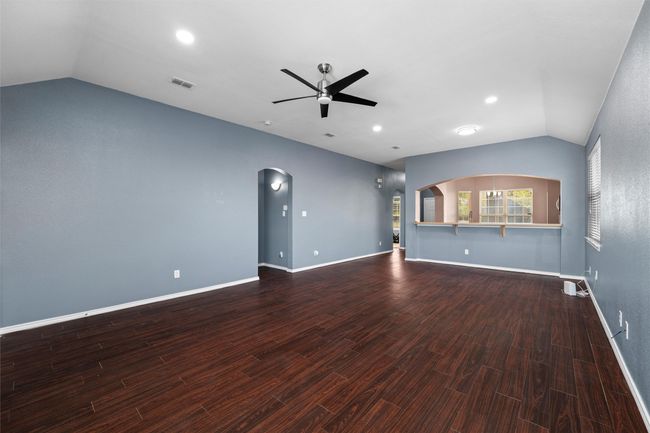 Unfurnished living room featuring arched walkways, a ceiling fan, vaulted ceiling, visible vents, and wood finished floors | Image 15