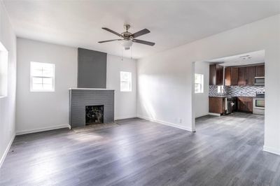 Unfurnished living room featuring a fireplace, hardwood / wood-style floors, sink, and ceiling fan | Image 2