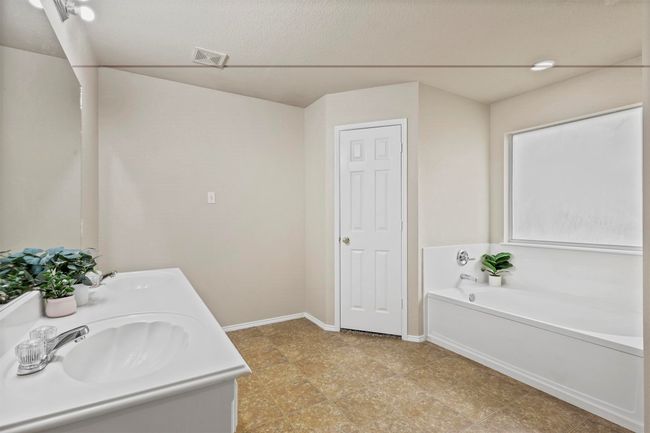 Bathroom with a garden tub, visible vents, baseboards, and a sink | Image 23