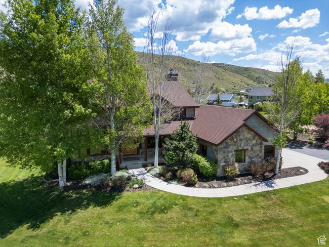 View of front facade with stone siding, a mountain view, a front lawn, and covered porch | Image 80