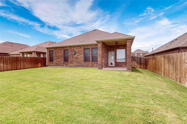 Rear view of house with brick siding, a ceiling fan, a patio area, a fenced backyard, and a shingled roof | Image 38