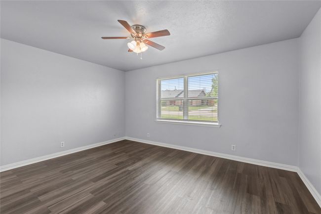 Empty room with dark wood-style floors and a ceiling fan | Image 17