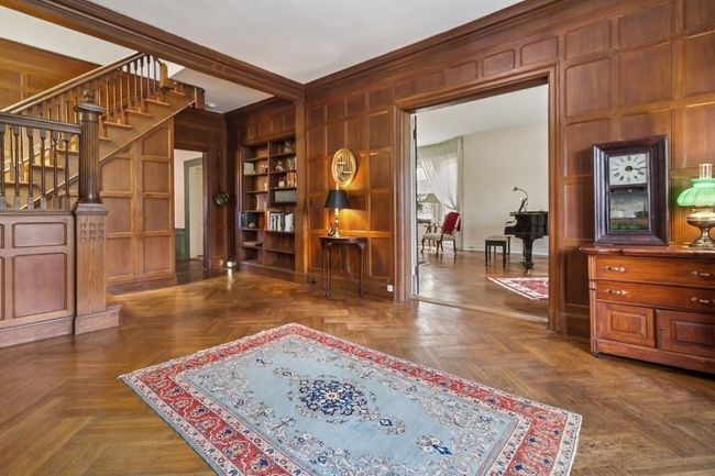 Sitting room featuring stairs, wooden walls, ornamental molding, a decorative wall, and built in shelves | Image 4