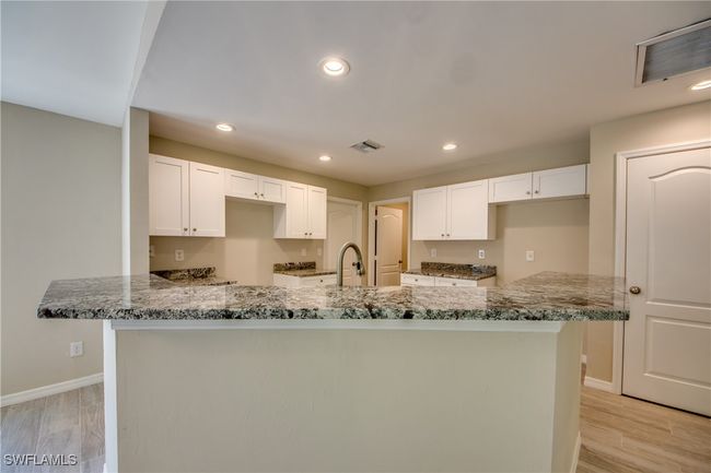 Kitchen with light stone counters, white cabinets, and visible vents | Image 22