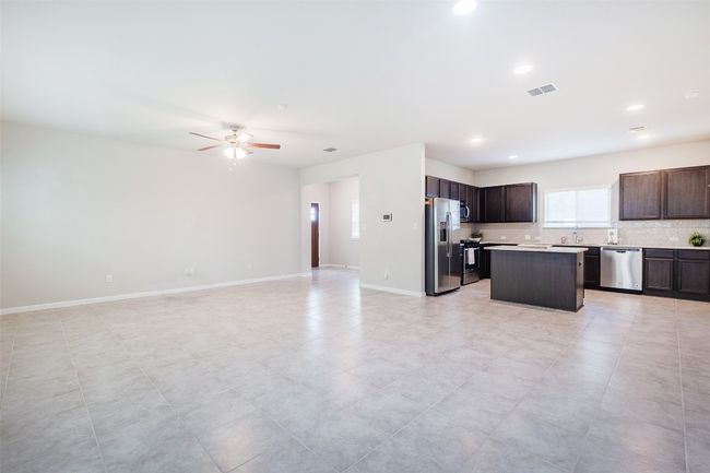Kitchen with a center island, baseboards, open floor plan, light countertops, and appliances with stainless steel finishes | Image 11