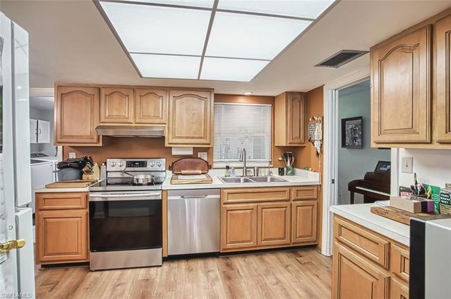 Kitchen featuring appliances with stainless steel finishes, light countertops, light wood-style flooring, and under cabinet range hood | Image 19