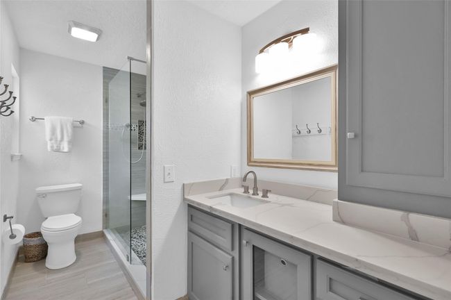 The remodeled Primary Bathroom has a granite countertop with painted wood cabinets/drawers and storage tower, chrome faucet and updated mirror and light fixture. | Image 17