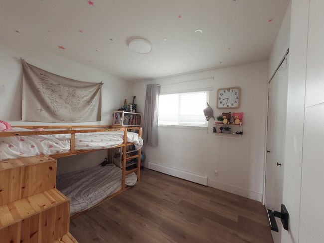 Bedroom with wood finished floors, a baseboard heating unit, and baseboards | Image 21