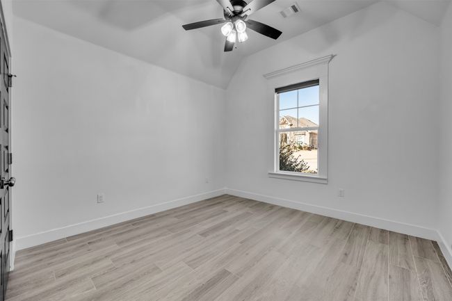 Empty room with vaulted ceiling, a ceiling fan, light wood-type flooring, baseboards, and visible vents | Image 17