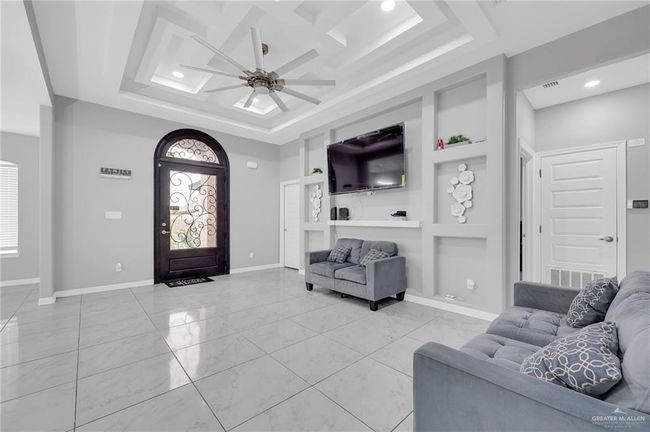 Living area featuring a ceiling fan, built in features, recessed lighting, and a raised ceiling | Image 7