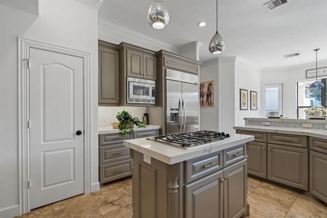 Another view of the kitchen, highlighting the expansive island and quartz countertops. This space effortlessly combines beauty and functionality, ideal for cooking and socializing. | Image 11