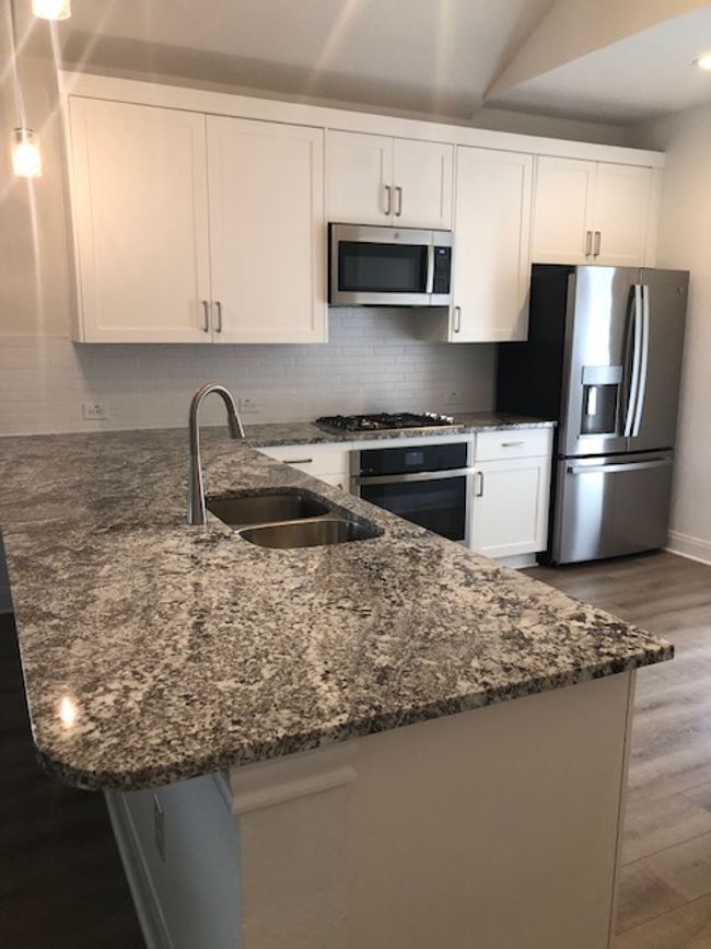 Kitchen featuring fridge, gas range, oven, a peninsula, granite countertops, and recessed lighting | Image 9