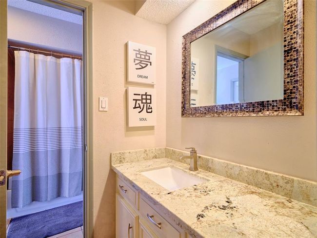 The connecting bathroom features an updated vanity with a granite countertop. | Image 25