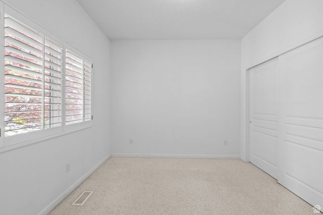 Unfurnished bedroom featuring carpet floors, visible vents, and multiple windows | Image 25
