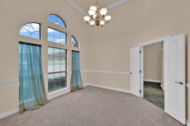 Spare room with a chandelier, carpet, crown molding, and a high ceiling | Image 16