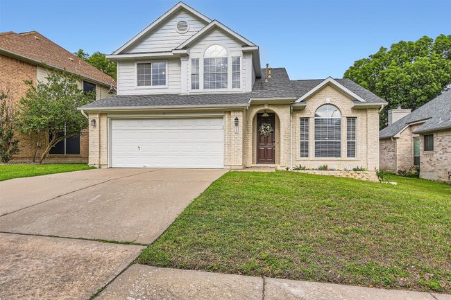 Traditional home featuring a garage, driveway, a front yard, brick siding, and roof with shingles | Image 4
