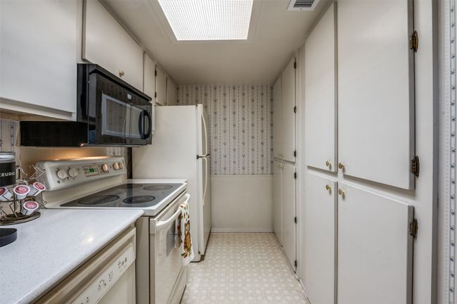 Kitchen featuring wallpapered walls, white appliances, light floors, light countertops, and white cabinets | Image 10