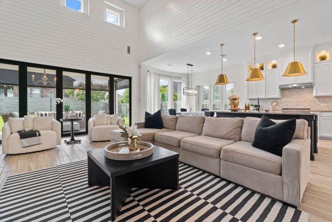 Living area featuring a high ceiling, light wood-style flooring, a chandelier, and recessed lighting | Image 8
