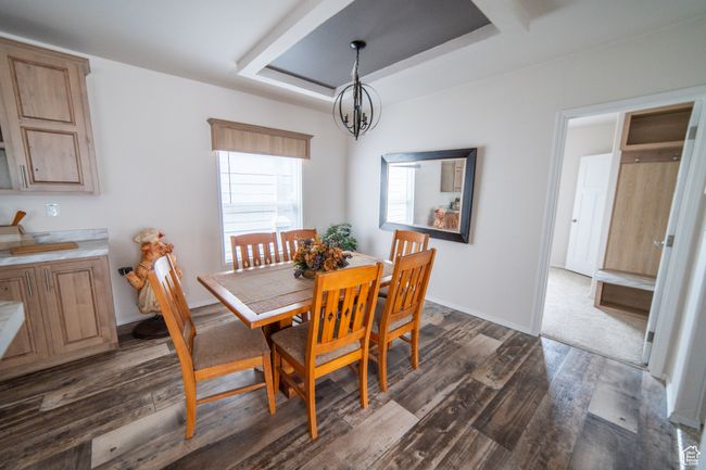 Dining space featuring dark wood-style floors, an inviting chandelier, and a tray ceiling | Image 61