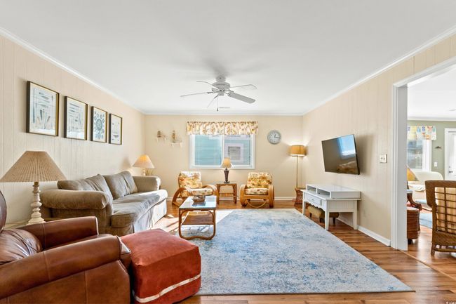 Living room featuring hardwood / wood-style flooring, ceiling fan, and crown molding | Image 9