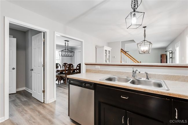 Kitchen with stainless steel dishwasher, a sink, a chandelier, dark cabinetry, and light countertops | Image 10