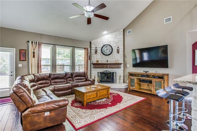 Living area featuring ceiling fan, dark wood-style floors, a stone fireplace, healthy amount of natural light, and high vaulted ceiling | Image 6