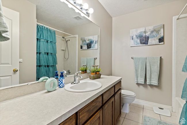 Full bathroom with vanity, toilet, tile patterned flooring, a textured ceiling, and baseboards | Image 14