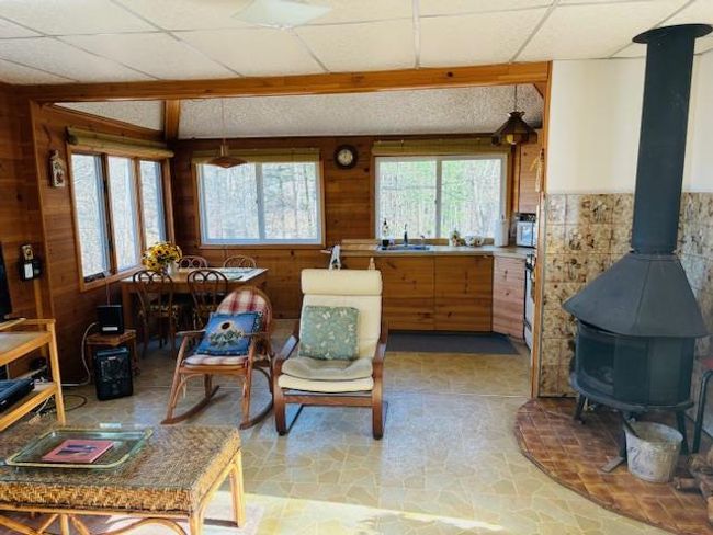 Living area featuring sink, a wood stove, a drop ceiling, and wood walls | Image 4