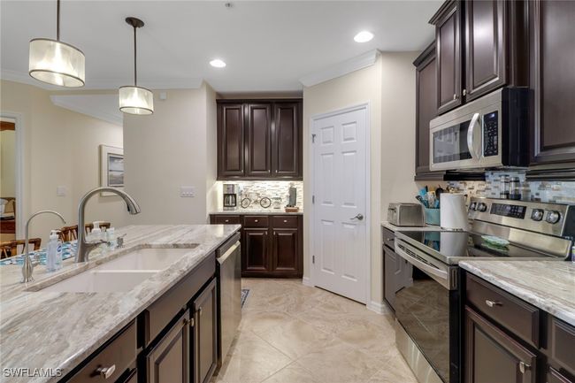 Kitchen with backsplash, ornamental molding, a sink, and stainless steel appliances | Image 8