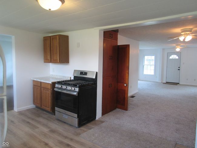 kitchen with gas range, a ceiling fan, brown cabinets, light countertops, and light wood-style floors | Image 10