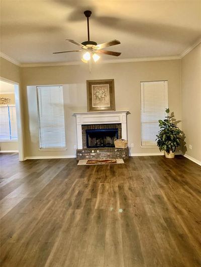 Unfurnished living room featuring crown molding, dark hardwood / wood-style floors, a fireplace, and ceiling fan | Image 3