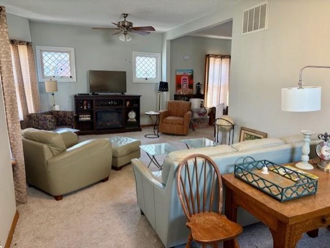 Carpeted living area featuring a ceiling fan, a textured ceiling, and visible vents | Image 7