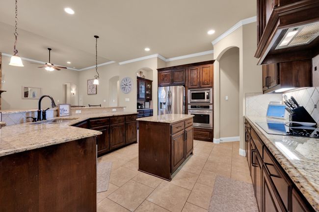 Kitchen with arched walkways, stainless steel appliances, a sink, ornamental molding, and backsplash | Image 9