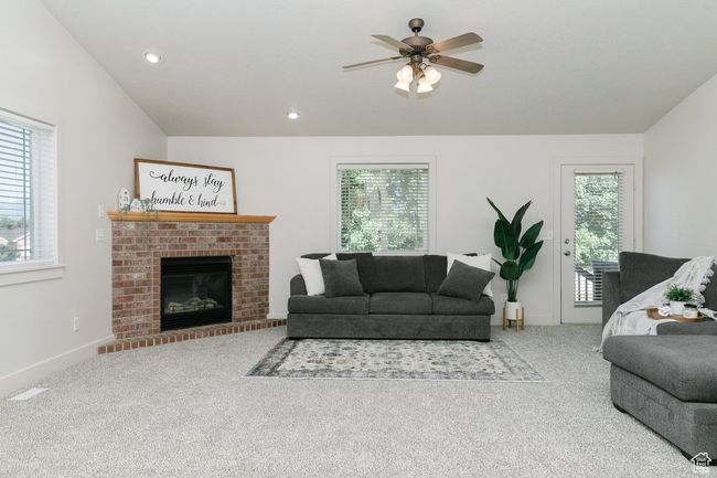 Living room featuring healthy amount of natural light, carpet floors, a ceiling fan, a fireplace, and recessed lighting | Image 5