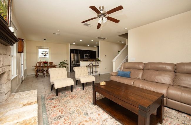 Living room with stairway, ceiling fan, and baseboards | Image 11