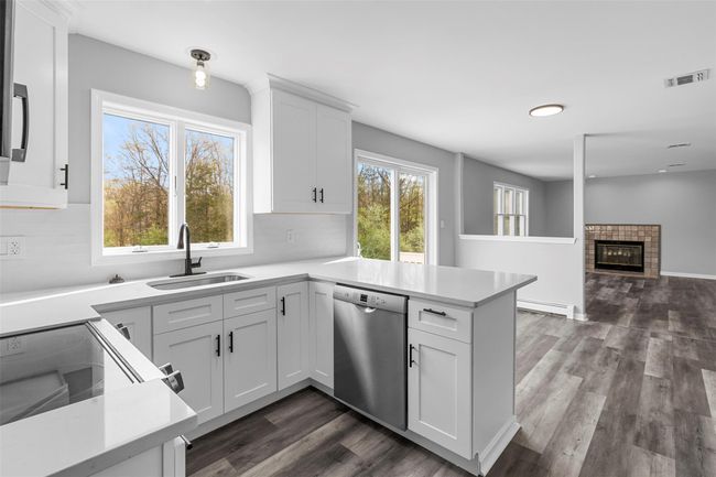 Kitchen with electric stove, stainless steel dishwasher, a sink, visible vents, and a peninsula | Image 6