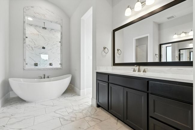 Full bath with marble look tiles, a freestanding bath, vanity, and a marble finish shower | Image 25
