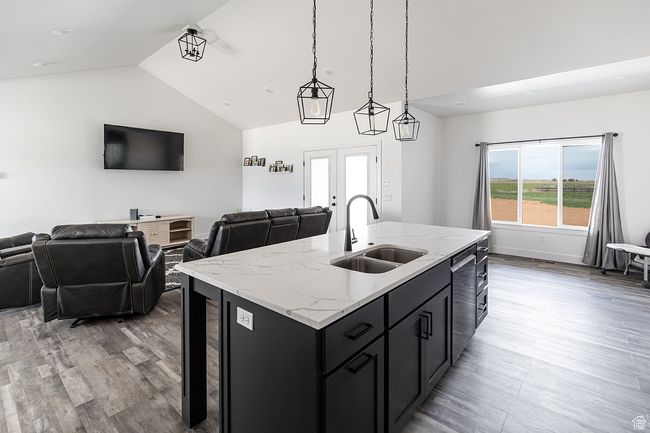 Kitchen featuring stainless steel dishwasher, dark cabinets, light wood-style floors, a sink, and open floor plan | Image 8