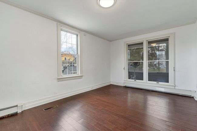 Empty room featuring baseboard heating, wood finished floors, and baseboards | Image 12