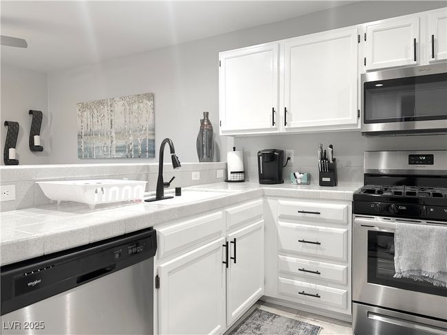 Kitchen featuring white cabinets, a sink, appliances with stainless steel finishes, light countertops, and backsplash | Image 13