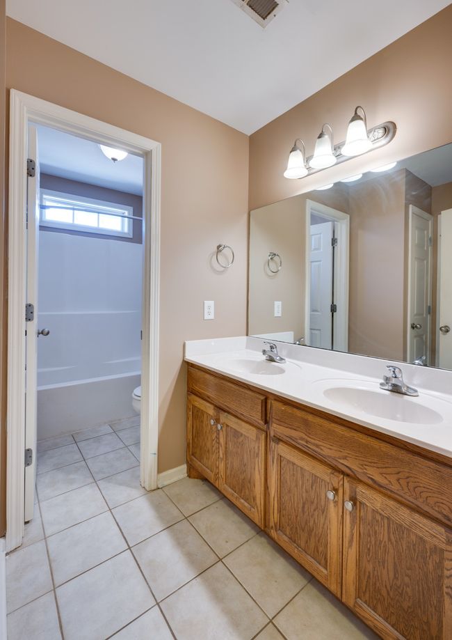 Upstairs full bathroom featuring his and hers sinks, extra storage closets, and tile floors. | Image 29