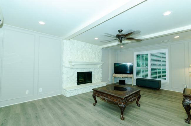 Living room featuring a decorative wall, light wood finished floors, a fireplace, a ceiling fan, and recessed lighting | Image 4