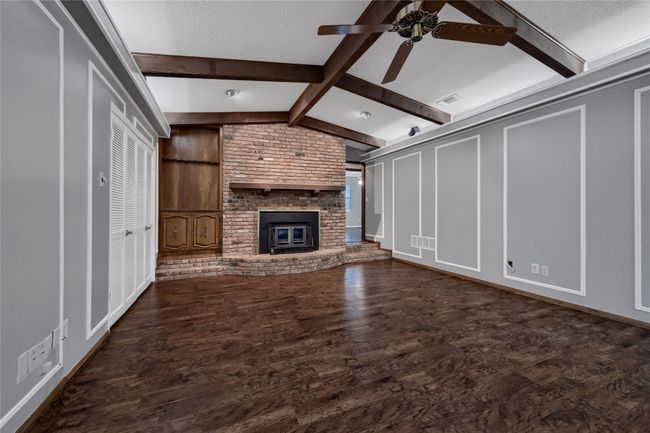 Unfurnished living room with a decorative wall, ceiling fan, lofted ceiling with beams, a textured ceiling, and visible vents | Image 10