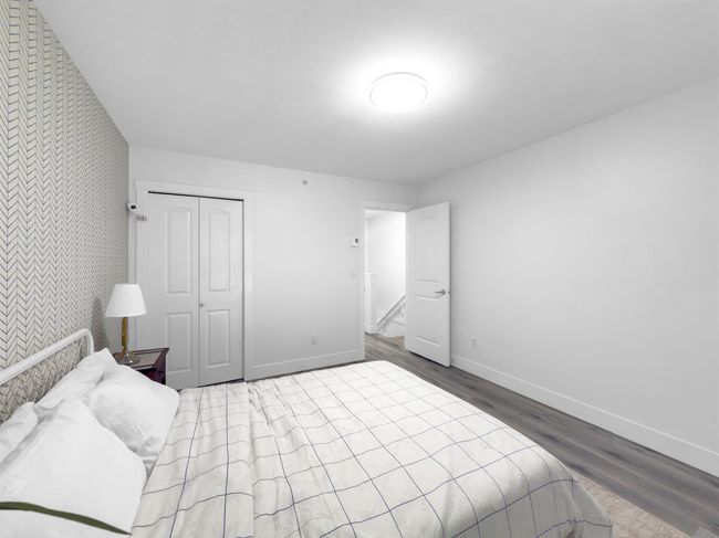 Bedroom with wallpapered walls, an accent wall, baseboards, wood finished floors, and a closet | Image 16