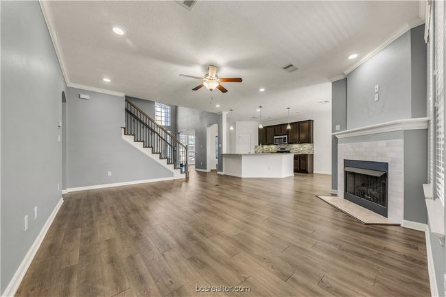 Unfurnished living room with ceiling fan, a fireplace, ornamental molding, and wood-type flooring | Image 14