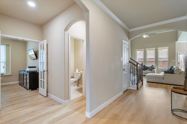 Hall featuring arched walkways, light wood-style floors, ornamental molding, and baseboards | Image 4