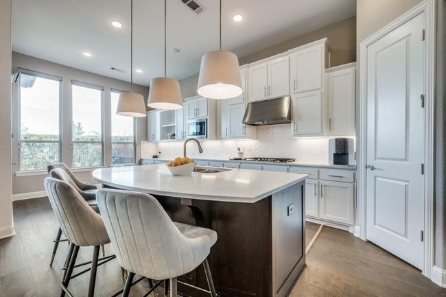 Kitchen with under cabinet range hood, appliances with stainless steel finishes, a sink, a center island with sink, and decorative backsplash | Image 12