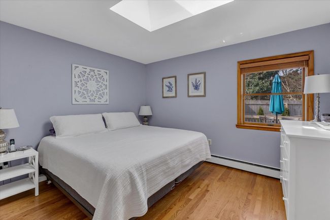 Primary bedroom with a skylight and hardwood floors | Image 6