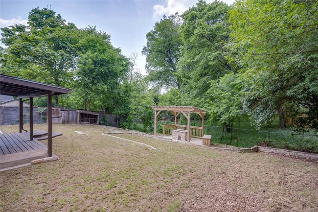 View of yard featuring a wooden deck, a pergola, and a fenced backyard | Image 28